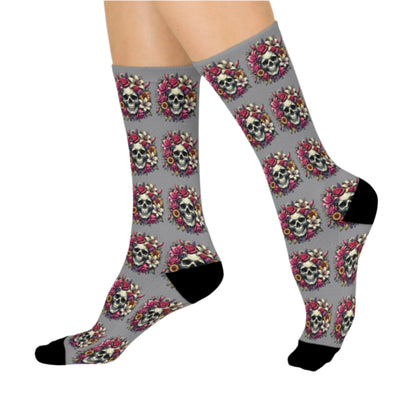 A pair of Lily Skull Crew Socks featuring a repeating pattern of skulls surrounded by lilies and roses on a gray background with black toe and heel accents. These socks blend edgy and floral designs, fitting women's size 5 US to men's size 12 US. From The Killer Tee.